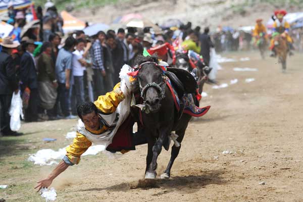 A ceremonial scarf is the target for a rider as the Ongkor Festival, a traditional Tibetan celebration to prepare for a bumper harvest, is staged in Lhasa on Thursday. PHOTO BY LI ZHOU / FOR CHINA DAILY